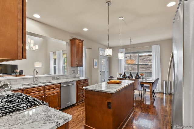 8741 E 29th Ave, Denver, CO 80238 - kitchen featuring a center island, a sink, stainless steel appliances, brown cabinetry, and dark wood finished floors