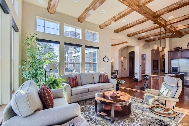 living room featuring beamed ceiling, dark hardwood / wood-style flooring, and a towering ceiling