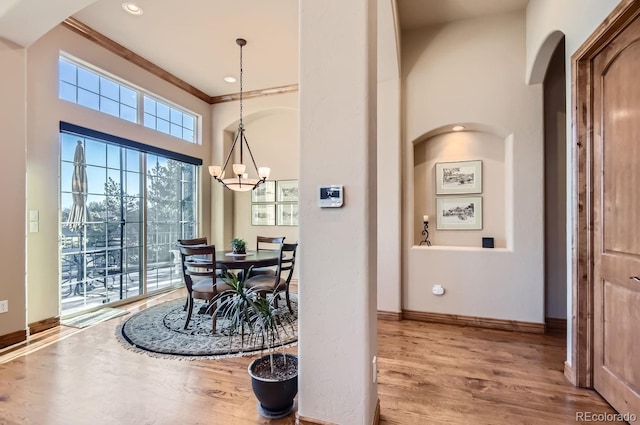 dining space with crown molding, hardwood / wood-style floors, and a notable chandelier