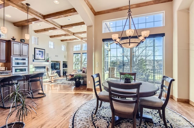 dining space featuring a high ceiling, light hardwood / wood-style flooring, a wealth of natural light, and an inviting chandelier