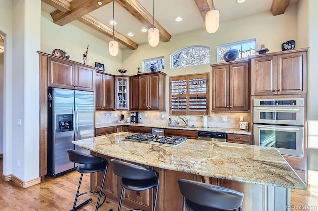 kitchen featuring beam ceiling, light wood-type flooring, stainless steel appliances, and tasteful backsplash