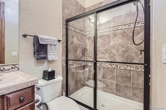 bathroom featuring vanity, toilet, and a shower with door