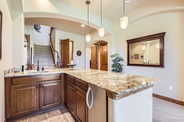 kitchen with sink, hanging light fixtures, light stone counters, kitchen peninsula, and light carpet