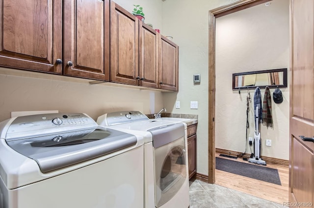 washroom with cabinets, sink, light tile patterned flooring, and washer and dryer