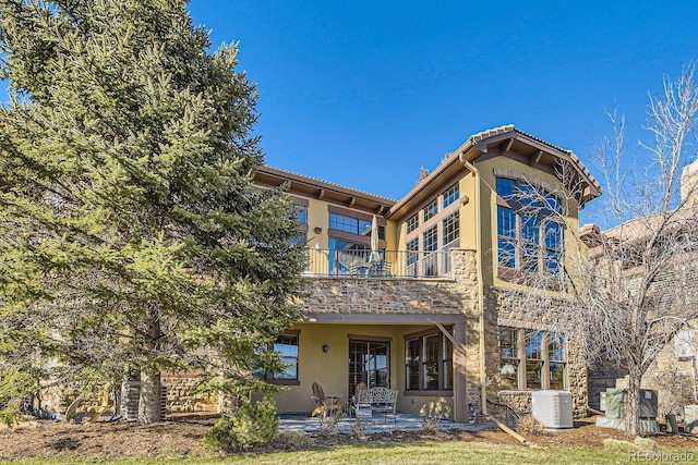 rear view of house with a balcony, a patio area, and central air condition unit