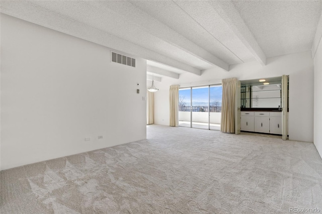 unfurnished living room with light carpet, a textured ceiling, and beam ceiling