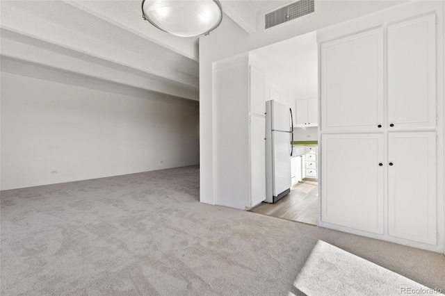 unfurnished bedroom featuring white refrigerator and light colored carpet