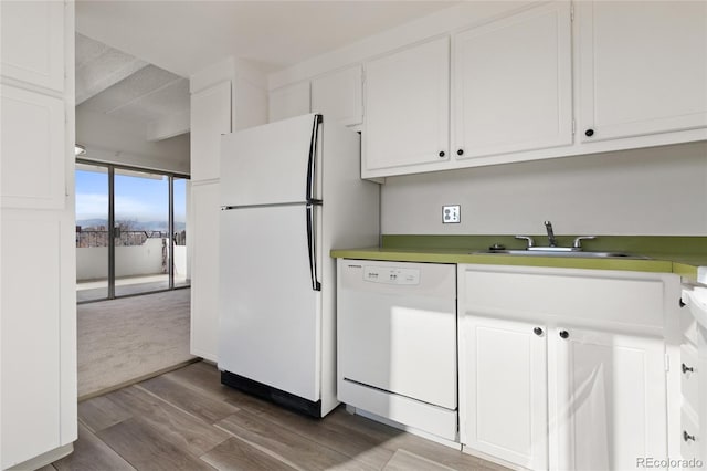 kitchen featuring sink, white appliances, white cabinets, and hardwood / wood-style flooring