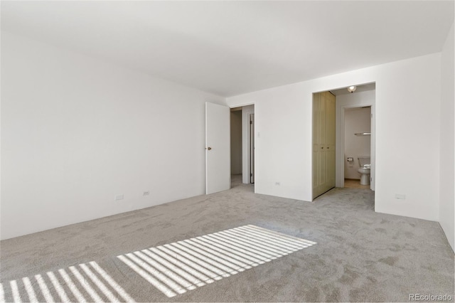 unfurnished bedroom with light colored carpet and ensuite bath