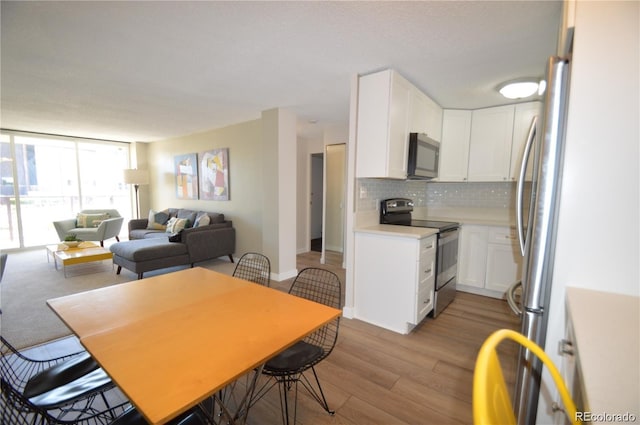 kitchen featuring stainless steel appliances, light countertops, decorative backsplash, light wood-style floors, and white cabinetry