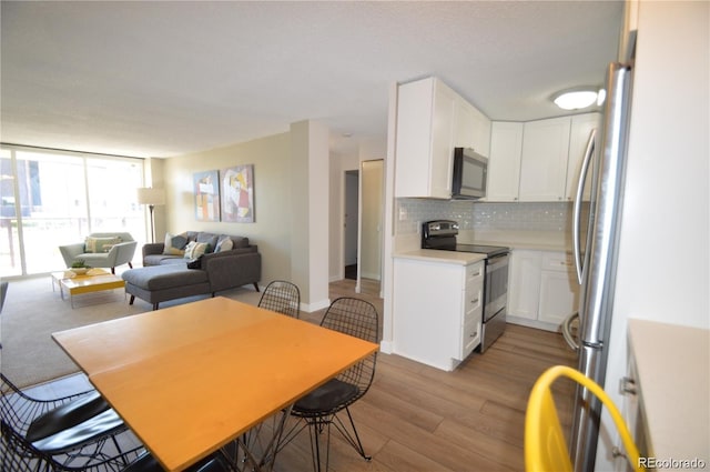 2225 Buchtel Blvd Unit 202, Denver, CO 80210 - dining space with light wood finished floors, baseboards, and floor to ceiling windows