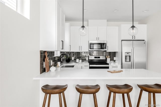 3955 W 13th Ave, Denver, CO 80204 - kitchen featuring appliances with stainless steel finishes, tasteful backsplash, a peninsula, light countertops, and white cabinets