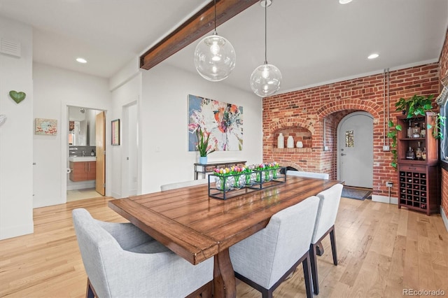 dining area featuring beam ceiling, recessed lighting, arched walkways, brick wall, and light wood finished floors