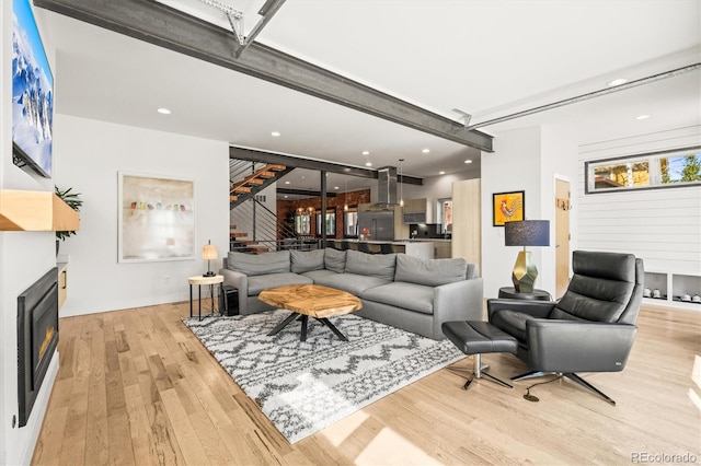 living area with stairway, recessed lighting, a lit fireplace, and wood finished floors