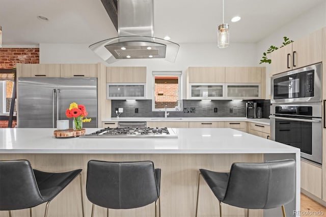 kitchen featuring appliances with stainless steel finishes, island exhaust hood, modern cabinets, and a sink