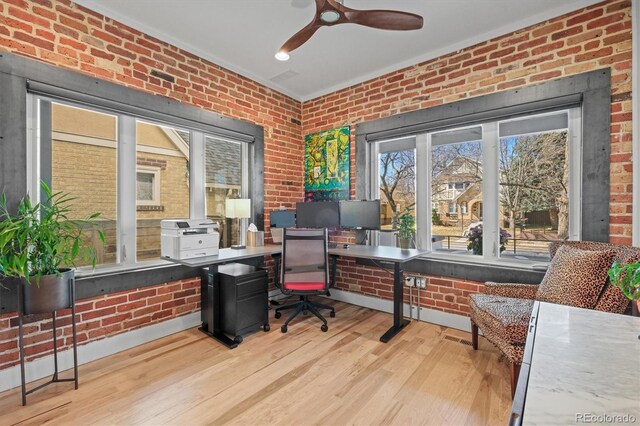 home office featuring ceiling fan, brick wall, baseboards, and wood finished floors