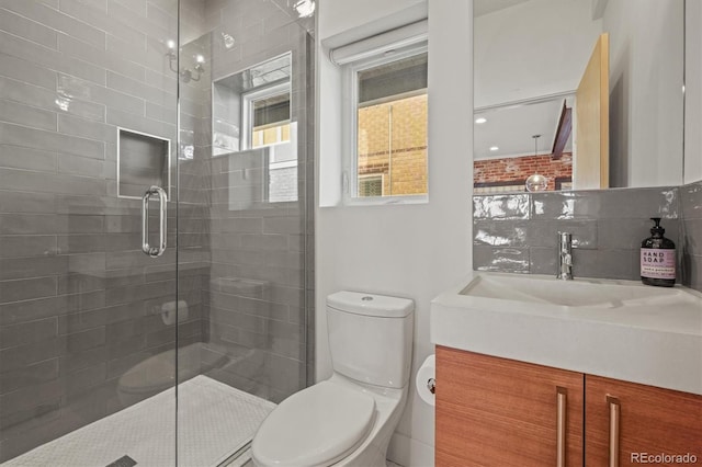 bathroom featuring decorative backsplash, toilet, vanity, and a stall shower