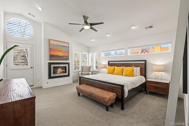 bedroom featuring visible vents, light carpet, lofted ceiling, and a glass covered fireplace