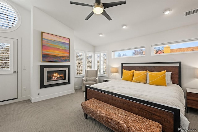 carpeted bedroom featuring visible vents, a glass covered fireplace, baseboards, ceiling fan, and vaulted ceiling