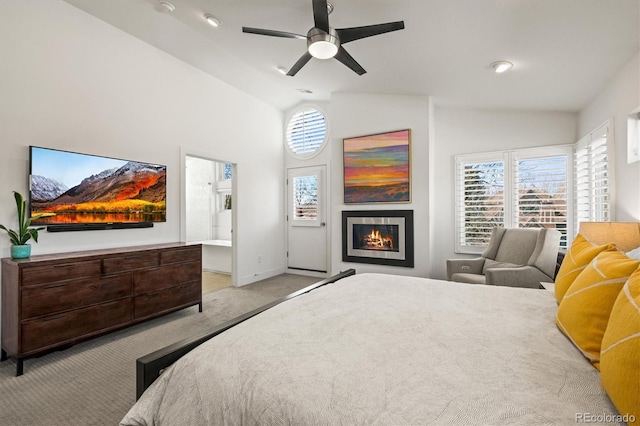 carpeted bedroom featuring baseboards, lofted ceiling, a lit fireplace, and a ceiling fan