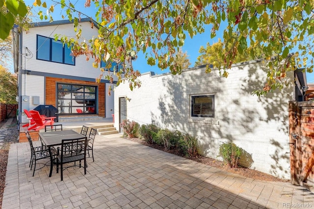 back of house featuring brick siding and a patio