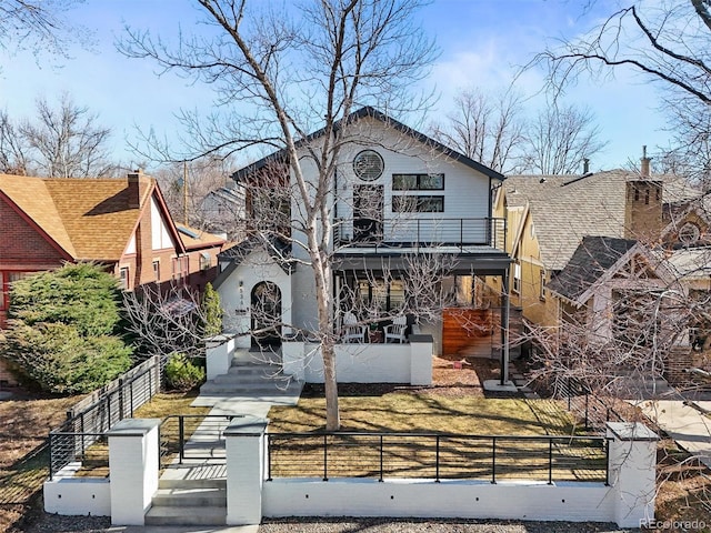 view of front of home with a balcony, covered porch, and a fenced front yard