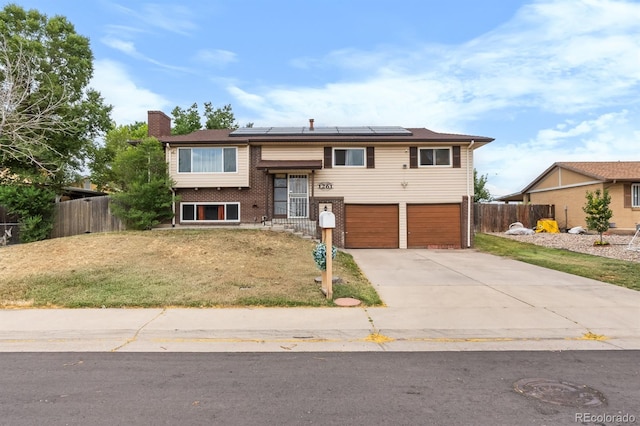1261 Eagle St, Aurora, CO 80011 - raised ranch featuring an attached garage, concrete driveway, solar panels, brick siding, and a chimney