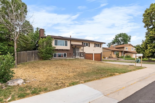 1261 Eagle St, Aurora, CO 80011 - split foyer home with a chimney, a garage, concrete driveway, and brick siding
