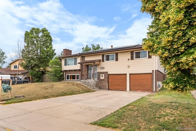 1261 Eagle St, Aurora, CO 80011 - split foyer home featuring a chimney, brick siding, a garage, driveway, and roof mounted solar panels