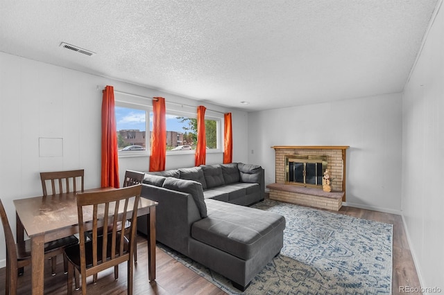 1261 Eagle St, Aurora, CO 80011 - living room with wood finished floors, a textured ceiling, and a brick fireplace