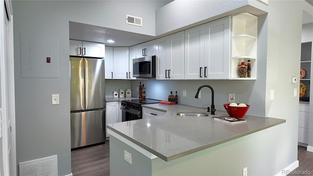 kitchen featuring sink, dark hardwood / wood-style flooring, kitchen peninsula, white cabinets, and appliances with stainless steel finishes