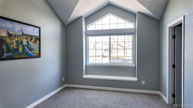 carpeted empty room featuring vaulted ceiling