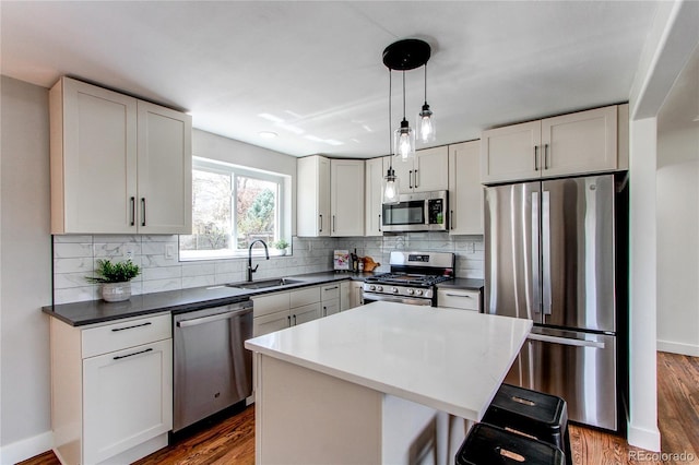 6220 W 11th Pl, Lakewood, CO 80214 - kitchen with stainless steel appliances, dark wood-style floors, tasteful backsplash, a breakfast bar, and white cabinets