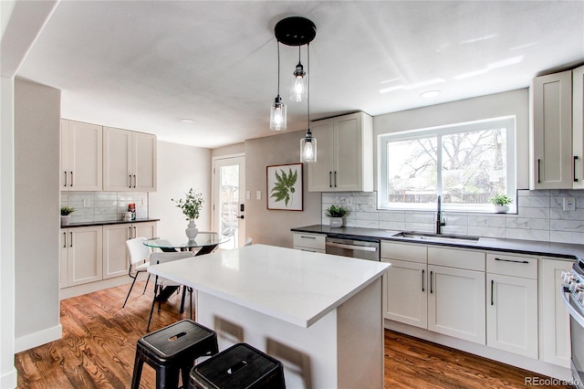 6220 W 11th Pl, Lakewood, CO 80214 - kitchen featuring tasteful backsplash, wood finished floors, hanging light fixtures, a breakfast bar area, and dark countertops