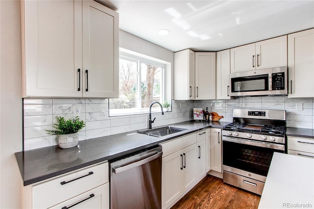 6220 W 11th Pl, Lakewood, CO 80214 - kitchen with appliances with stainless steel finishes, dark countertops, white cabinets, and dark wood-style floors