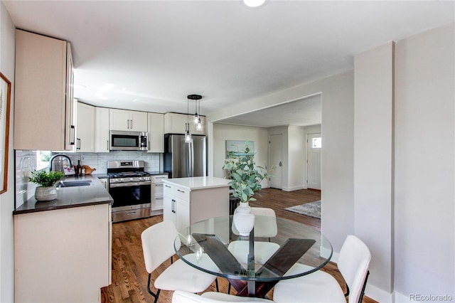 6220 W 11th Pl, Lakewood, CO 80214 - kitchen with appliances with stainless steel finishes, a center island, dark wood-type flooring, and decorative backsplash