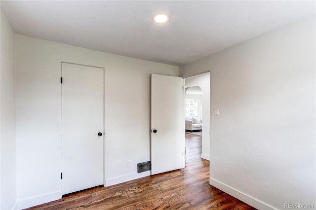 6220 W 11th Pl, Lakewood, CO 80214 - unfurnished bedroom with arched walkways, wood finished floors, and a closet