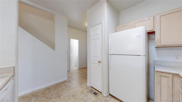 kitchen featuring light brown cabinets, white appliances, visible vents, baseboards, and light countertops