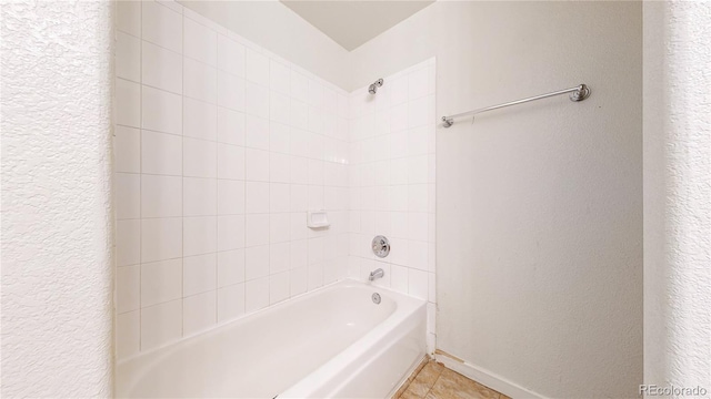 full bath with tile patterned floors, a textured wall, baseboards, and bathing tub / shower combination