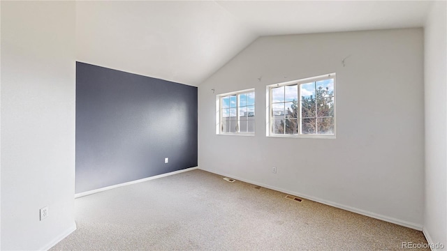 carpeted empty room featuring lofted ceiling and baseboards