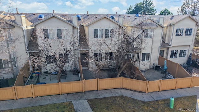 view of front of house with a fenced backyard, a patio, and central AC