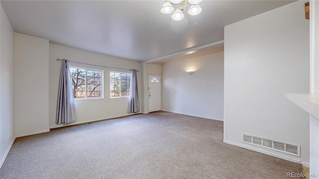 spare room featuring baseboards, visible vents, a chandelier, and carpet flooring