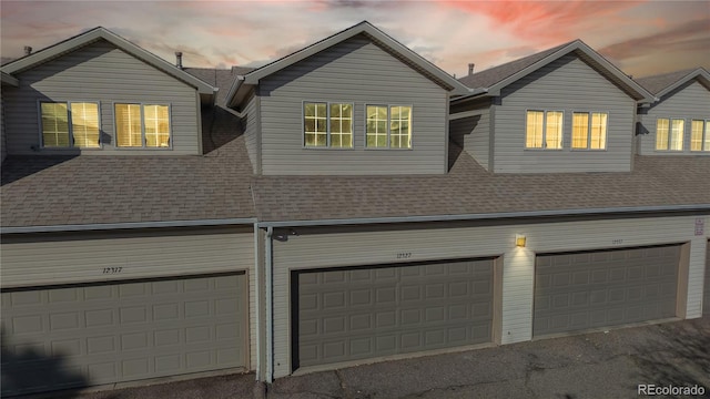 exterior space with an attached garage, roof with shingles, and driveway