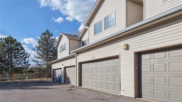 garage with aphalt driveway and fence