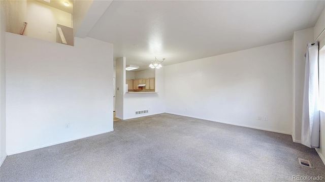 empty room with visible vents, baseboards, carpet flooring, and an inviting chandelier