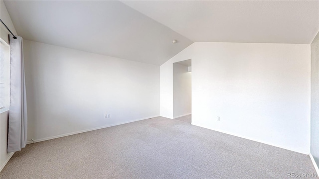 empty room with baseboards, light colored carpet, and vaulted ceiling