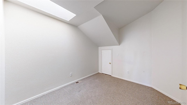 additional living space featuring carpet flooring, baseboards, visible vents, and lofted ceiling with skylight