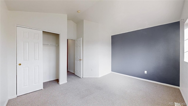 unfurnished bedroom featuring a closet, baseboards, carpet flooring, and lofted ceiling