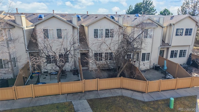 view of front of house with a patio area, a fenced backyard, and central AC