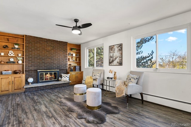 sitting room with built in shelves, ceiling fan, a fireplace, a baseboard radiator, and dark hardwood / wood-style flooring